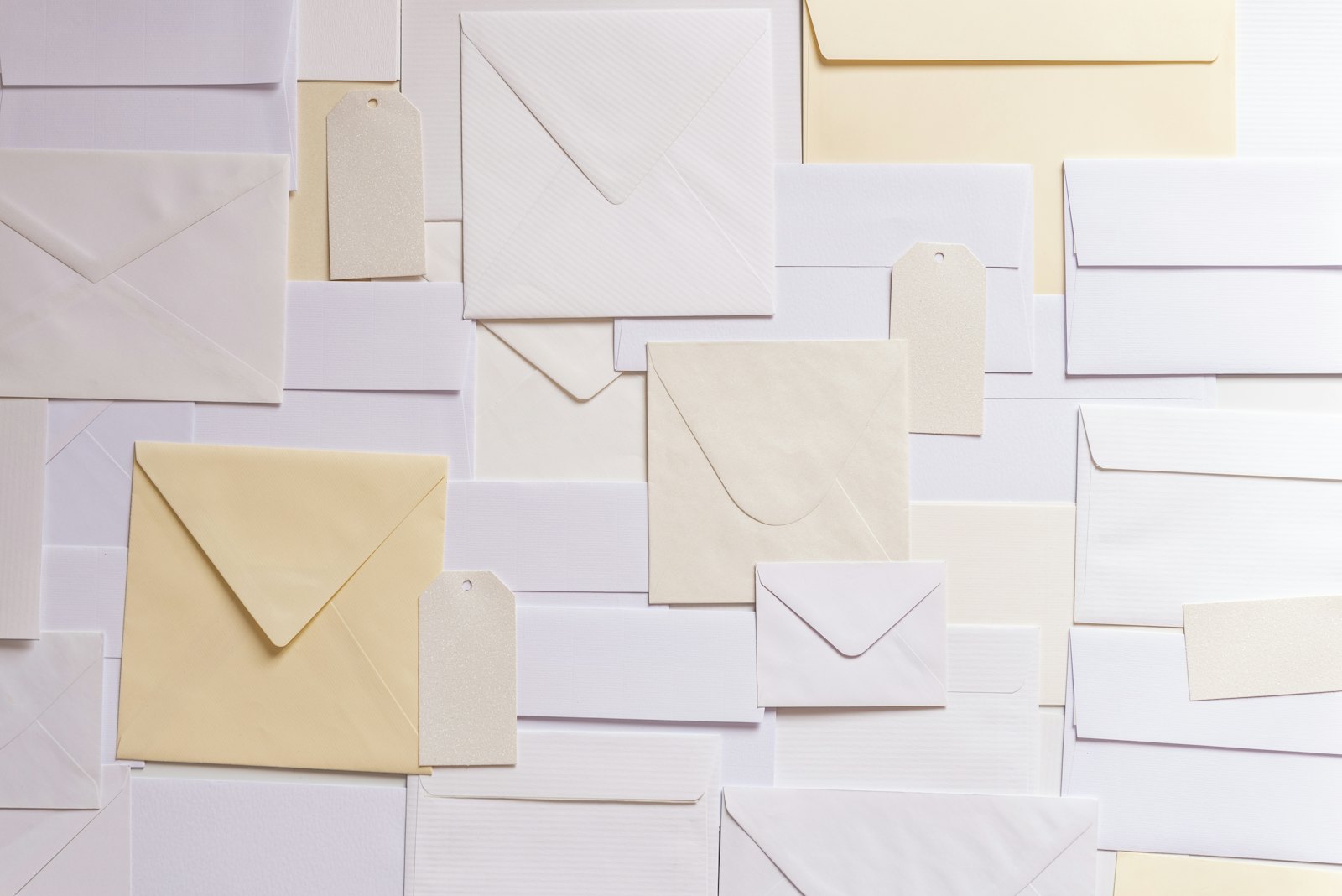 Blank envelopes in white and pale yellow, with a few paper tags, laid flat and overlapping.